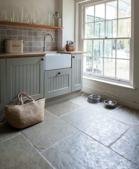 Kök med golv i ljus kalksten, stora stenplattor och naturligt ljusinsläpp